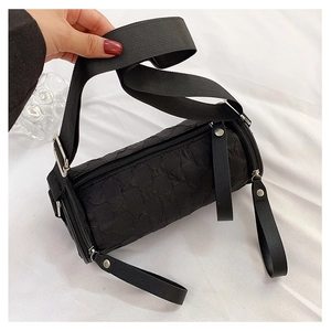 Detail of black cylindrical crossbody bag with textured fabric and wide shoulder strap