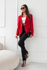 Dettaglio blazer rosso con bottoni metallici e pantaloni con spacco per donna