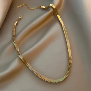 Detail of gold fish scale chain with lobster clasp on silk, made of stainless steel