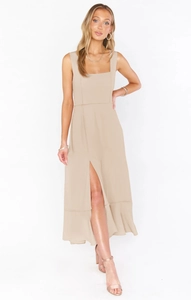 Detailed view of beige sleeveless dress featuring an elegant side slit and ruffled hemline