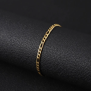 Detailed close-up of an 18K gold plated stainless steel Figaro chain bracelet on a black stand