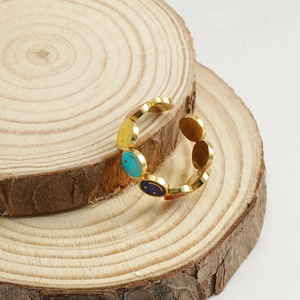 Detail of gold-plated stainless steel ring with colorful enamel smiley faces on wood