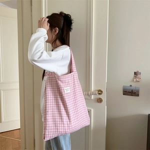 Close-up of pink and white plaid tote bag featuring woven texture and a fabric label