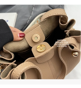 Detailed macro view of the brown leather bucket bag with magnetic snap closure mechanism