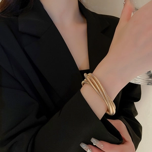 Detailed close-up of a layered gold elastic cuff bracelet showing intricate metal textures