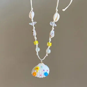 Detail of bohemian necklace featuring white scallop shell pendant and colorful bead accents