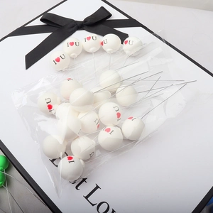 Macro view of white ball cake toppers with I heart U lettering and wire stems