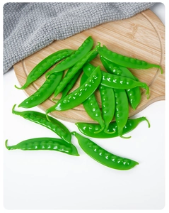 Detailed view of realistic green PVC pea pods on a wooden board for kitchen decor