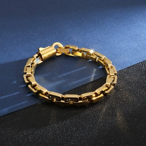 Detail of a golden cuban chain bracelet featuring a round push-lock clasp and geometric links
