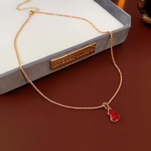 Detail of a gold-plated necklace with a red gourd pendant in a gray jewelry gift box