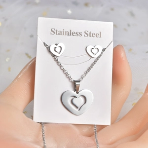 Macro detail of a silver stainless steel heart necklace and stud earrings jewelry set