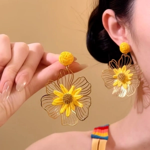 Prachtig detail van gele raffia bloem oorbellen met gouden draad bloemblaadjes