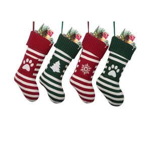 Four festive red and green knitted Christmas stockings with paw and tree patterns