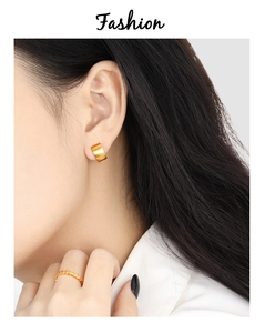 Detail shot of a minimalist wide gold hoop earring and textured ring on a fashion model
