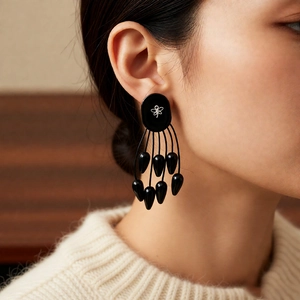 Gros plan de boucles d'oreilles à pompons noirs avec papillon argenté sur mannequin