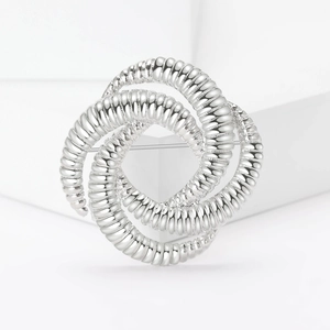 Modern silver geometric knot brooch in a spiral design on a minimalist white background