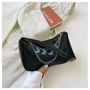 Detail of black PU leather underarm bag featuring silver chain and blue butterfly charms