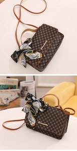 Close-up of brown patterned crossbody bag with silk scarf handle and golden logo
