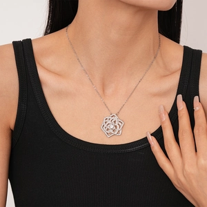 Detailed view of silver flower necklace with zircons on model neck with black top