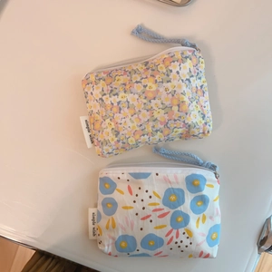 Detail of two floral cotton coin purses with blue and pink prints and braided zipper pulls