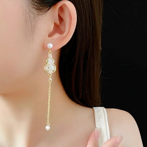 Elegant gold gourd tassel earrings with pearls on a model, showcasing Chinese style design