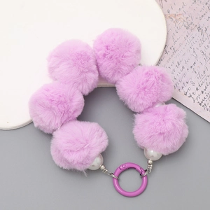 Close-up of purple faux fur pom pom keychain with white pearls and a purple metal clasp