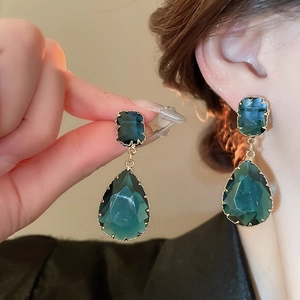 Detailed macro of vintage dark green zircon earrings with teardrop and square cut crystals