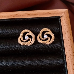 Detailed close-up of a vintage golden hollow earring with pearl in a jewelry box