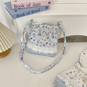 Détail du sac seau bleu clair à fleurs avec broderie de dentelle et motifs de dessins animés