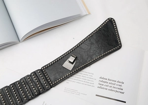 Close-up of black punk waist belt featuring dense square metal rivets on leather