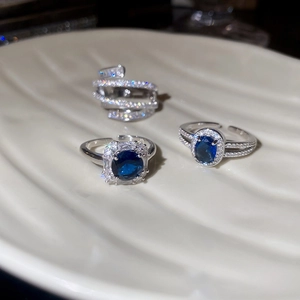 Detailed close-up of three blue zircon rings including square and oval designs on a plate