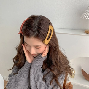 Matte finish D-shaped large hair clips in orange and brown colors worn by a model
