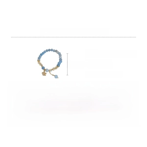 Détail d'un bracelet en perles bleu clair avec pendentif papillon doré et cristaux de zircon