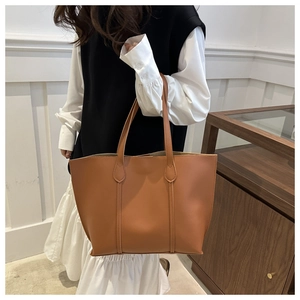 Detail of brown PU leather tote bag featuring sleek vertical stitching and slim straps