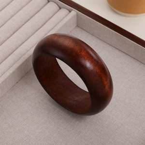 Macro shot of thick dark sandalwood bangle showing natural wood grain and polished texture