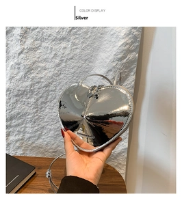 Detailansicht der herzförmigen silbernen Spiegeltasche mit Metallgriff und Schriftzug