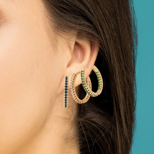 Close-up of gold hoop earrings with blue, clear, and green zircon stones on model