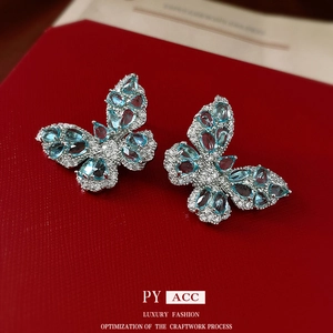 Elegant silver butterfly earrings with blue cubic zirconia on red textured background