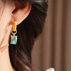 Detailed close-up of a blue enamel elephant pendant dangling from a yellow ring earring