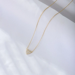 Elegant s925 silver heart necklace with pavé cubic zirconia on soft white fabric background