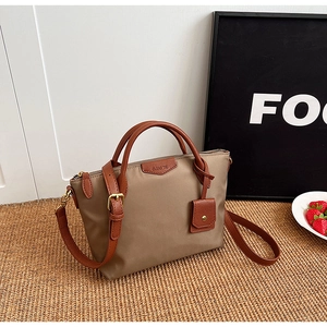 Detail of khaki nylon tote bag with brown litchi leather handles and Clearyk brand logo