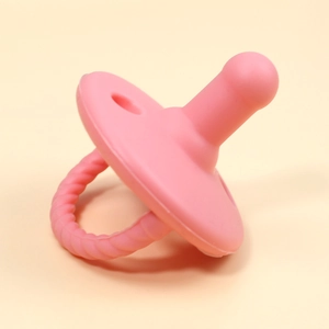 Close-up of pink silicone baby pacifier with textured ring handle and soft round nipple