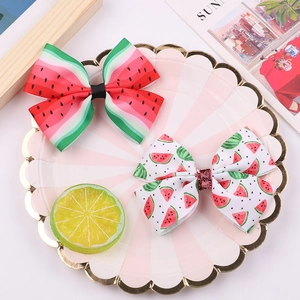 Cute watermelon print bow hair clips for girls set on a decorative pink stripe plate