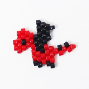 Macro detail of red and black handmade miyuki bead dinosaur craft for DIY jewelry making