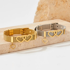 Gold and silver mesh watch band bracelets with intertwined hearts on a stone surface