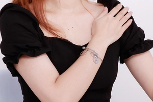 Silver stainless steel charm bracelet featuring heart and figure pendants on model wrist