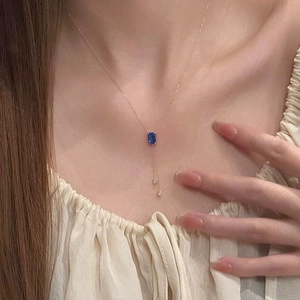 Collier élégant en or rose avec pendentif cristal bleu rectangulaire et accents de glands