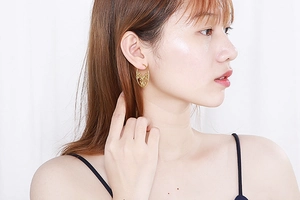 Close-up of a woman wearing these gold hollow floral hoop earrings in stainless steel