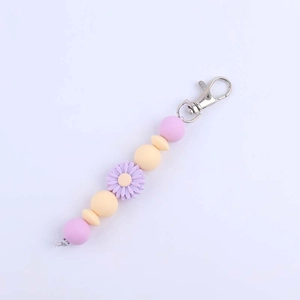 Close-up of silicone daisy charm keychain with purple and yellow beads on silver clasp