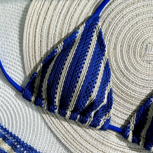 Detail of blue and beige striped crochet bikini top with lace-up ties on straw mat